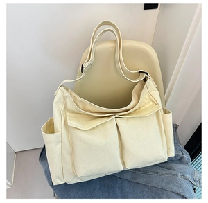 Close-up of cream canvas tote bag with large front pockets on a minimalist chair