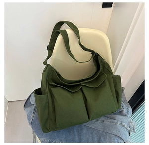 Detail view of military green canvas tote bag with large utility pockets and wide strap