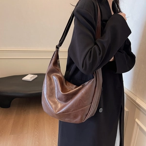 Brown vintage hobo tote bag with adjustable strap worn as a stylish crossbody bag