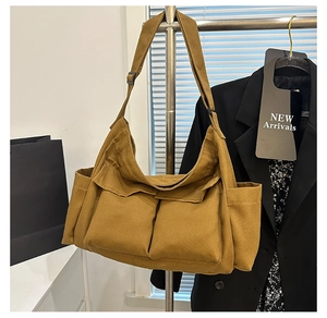 Detail view of khaki canvas crossbody bag with large front pockets and wide strap