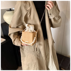 Détail du sac bandoulière tissé jaune avec poignée en perles et doublure en satin