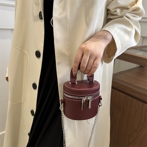 Mini burgundy cylindrical leather handbag with contrast stitching and silver chain strap
