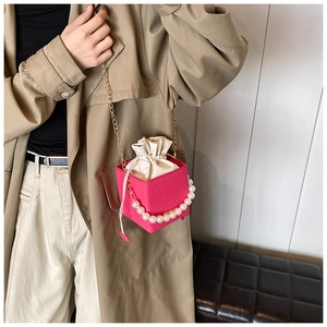 Détail du sac seau fuchsia en peau de serpent avec anse perle et bandoulière chaîne