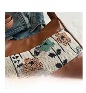 Detail of bohemian embroidery and floral woven texture on a vintage brown leather bag