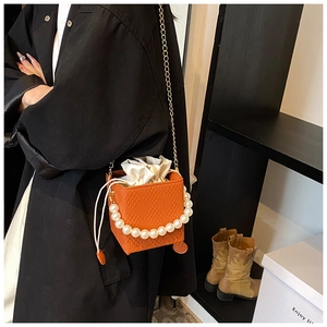 Sac à bandoulière tressé orange avec poignée perle et chaîne dorée sur mannequin