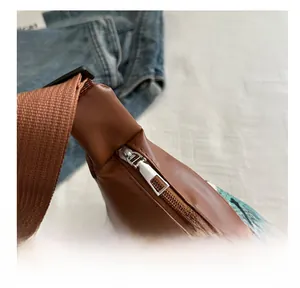 Detail shot of smooth silver metal zipper and green jacquard weave on brown tote bag