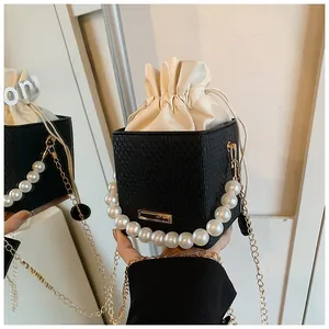 Détail du sac carré tissé avec poignée élégante en perles et bandoulière dorée