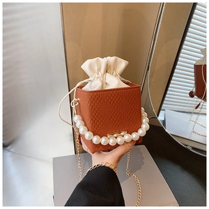Detail of woven square bucket bag with pearl handle and white satin drawstring inner