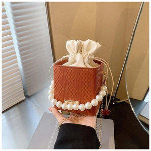 Détail du sac boîte tressé marron avec anse en perles et doublure à cordon blanc
