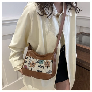 Detail of vintage moon bag featuring floral embroidery and brown PU leather strap