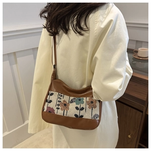 Detail of floral jacquard fabric and brown leather strap on a stylish tote bag