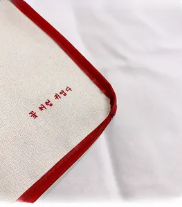 Macro detail of cream canvas tote bag with red leather edge and Korean print