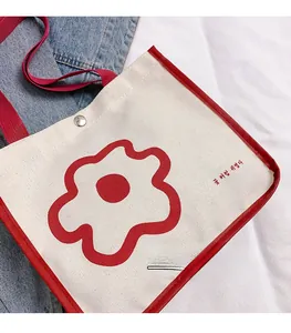 Close-up of canvas tote bag featuring red flower print, snap button, and red shoulder straps