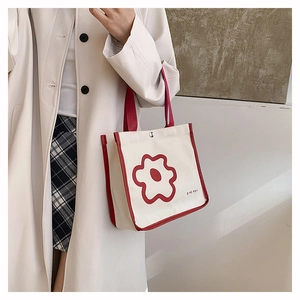 Detail of canvas tote bag with red floral pattern and button closure shown on model