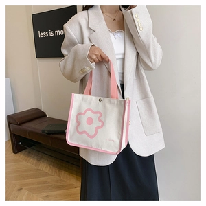 Chic beige canvas handbag featuring pink trim and minimalist floral print on a model