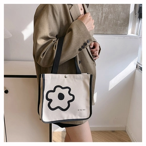 Detail of cream canvas tote bag with black floral print and secure metal snap closure