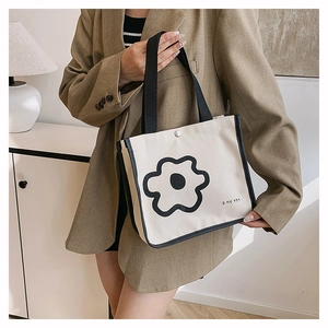 Detail of minimalist canvas tote with black floral print and contrast strap accents