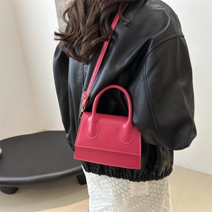 Minimalist fuchsia mini crossbody square bag shown with a model in an indoor setting