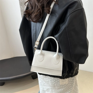 Minimalist white PU leather crossbody bag worn by model over a black leather jacket