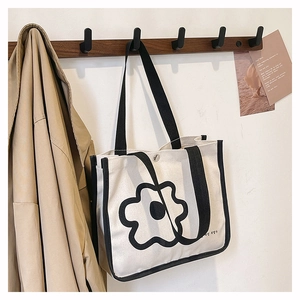 Detail of minimalist canvas tote bag featuring black floral print and contrast piping