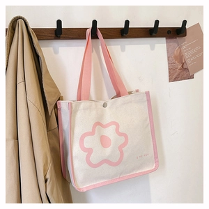 Close-up of cream canvas tote bag featuring pink floral print and contrast handles