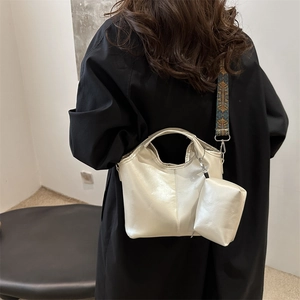 Borsa a secchiello beige con tracolla a motivi indossata da una modella in una stanza