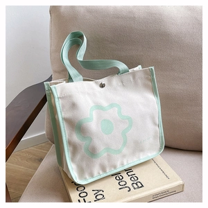 Detail of canvas tote bag featuring mint green piping and floral print on gray chair