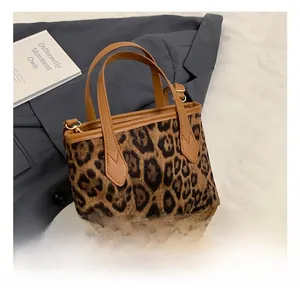 Detailed view of leopard print bucket bag featuring brown leather handle and metal D-ring hardware