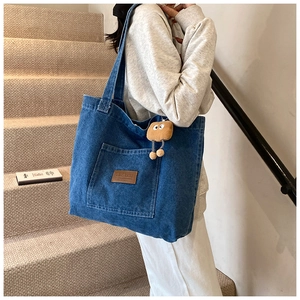 Détail du grand sac cabas en jean bleu avec patch en cuir et pendentif peluche mignon