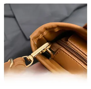 Macro detail of golden metal hook and premium zipper on the brown leather bucket bag