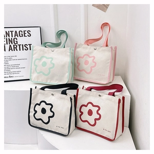 Detail view of four canvas tote bags with flower patterns and colorful handles