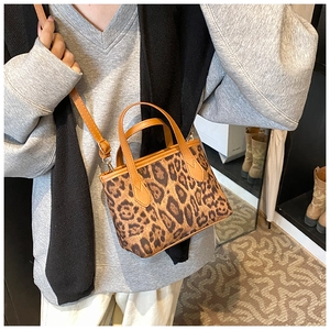 Detailed shot of leopard print handbag with brown leather straps on a casual outfit