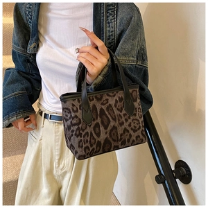 Close-up of leopard print bucket bag featuring black leather handles and reinforced stitching