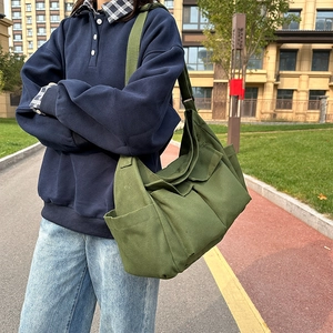 Army green large canvas tote bag with multi-pocket design shown on model outdoors