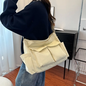 Minimalist cream canvas messenger bag with large utility pockets and adjustable strap