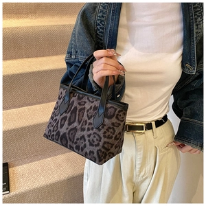 Detail of leopard print tote bag with black leather handle shown in a lifestyle setting