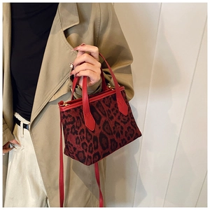Detail of red leopard print bucket bag featuring premium leather handles and texture