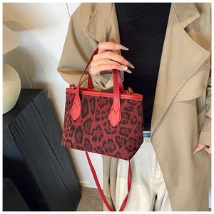 Close-up of red leopard print bucket bag with leather handles and gold hardware details
