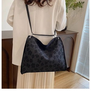 Détail du sac cabas noir avec motifs floraux floqués et fines lanières en cuir chic