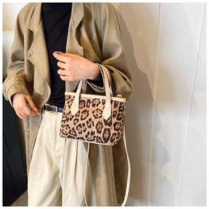 Detailed view of fashionable leopard print bucket bag with tan leather strap and handle