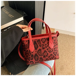 Close-up of leopard print bucket bag with red leather handles and wide shoulder strap