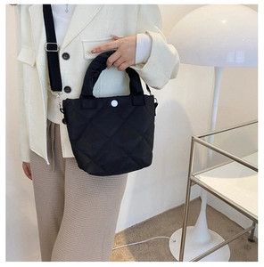Close-up of black quilted bucket bag with ruched handle and adjustable nylon strap