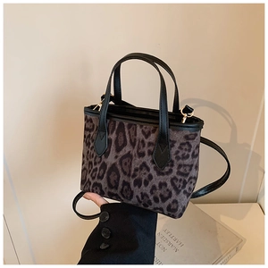 Detail of leopard print bucket bag with black leather handle and adjustable shoulder strap