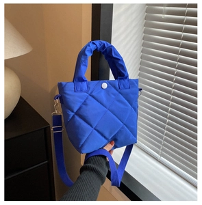Close-up of blue quilted bucket bag with padded handles and white snap button closure