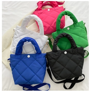 Detail of colorful quilted nylon handbags showing textured stitching and top handle