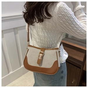 Detailed view of cream canvas and brown leather stitching on a retro saddle shoulder bag