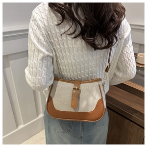 Detailed view of canvas shoulder bag with brown leather trim worn by a model