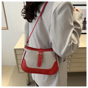 Detail view of woven canvas handbag with red leather trim and gold metal buckle