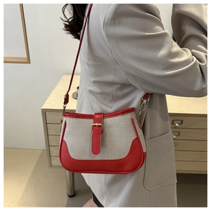 Detail of contrast stitching and gold buckle on a cream woven shoulder bag with red trim