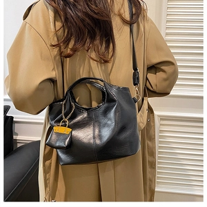 Detail view of large black bucket bag featuring lychee texture and gold chain charm